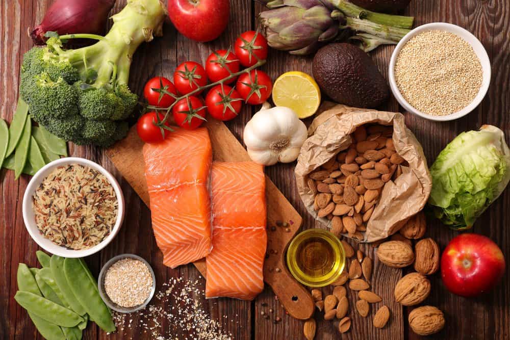 Table with foods including salmon, almonds, avacado, broccoli, garlic, and more.